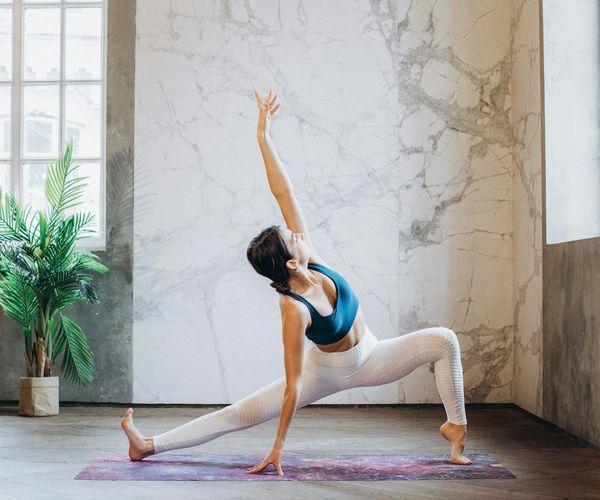 Person stretching peacefully in a bright, sunlit studio.
